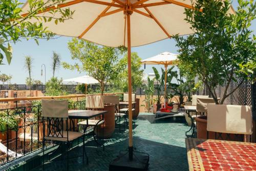 a patio with tables and chairs with an umbrella at Riad Anya & SPA in Marrakech