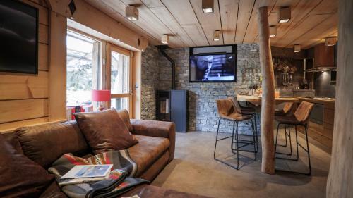 a living room with a couch and a kitchen with a table at Lodge plein pied avec jardin à 10min de Chamonix in Servoz