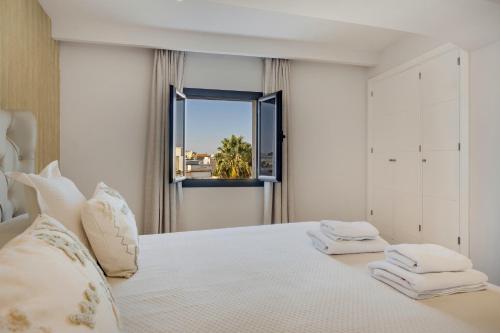 a bedroom with a white bed with a window at Calle Larga 48 golf incluido in Jerez de la Frontera