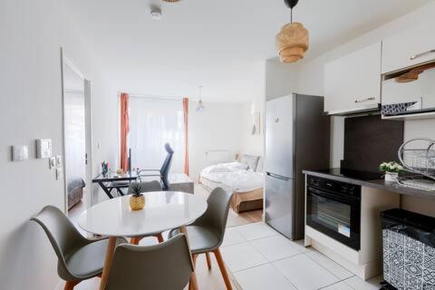 une cuisine avec une table et des chaises dans une pièce dans l'établissement Appartement neuf cozy, à Bezons