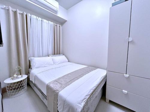 a small white bedroom with a bed and a dresser at The 3rd Staycation Near MOA, Airport, with FREE WIFI, Netflix in Manila