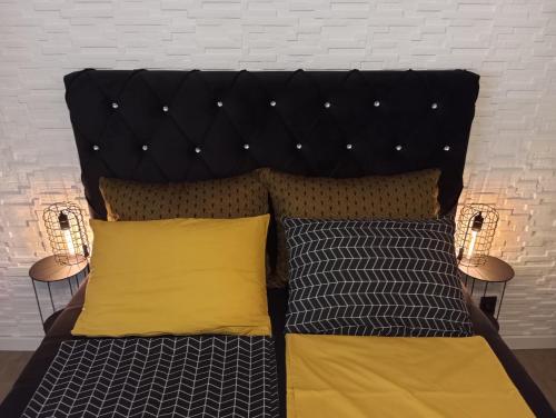 a bed with two yellow pillows and a headboard at Black Diamond Lux - deluxe riverside apartment in Senta