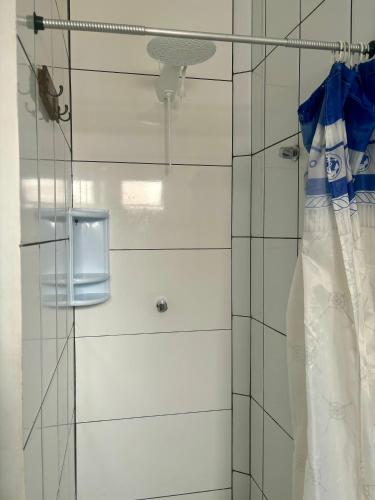 a shower with a glass door with a curtain at Pousada Escotilha in Arraial do Cabo