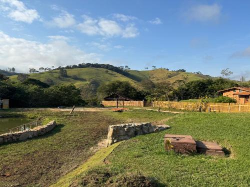 a field with a house and a hill in the background at Chale com hidro na Serra da Mantiqueira in Sapucaí-Mirim