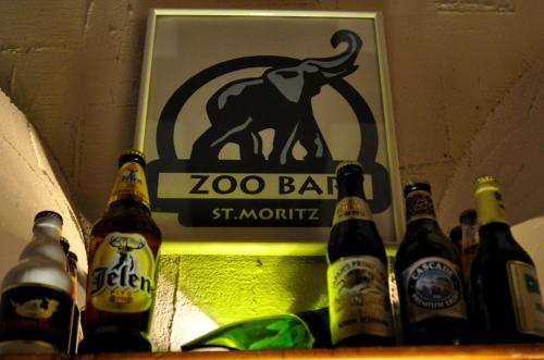 a group of beer bottles on a shelf with a zoo bar sign at Soldanella in St. Moritz