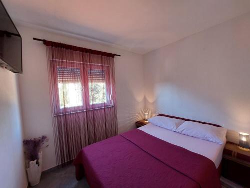 a bedroom with a bed with a purple blanket and a window at Tina in Kolan