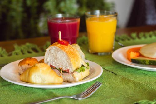 a sandwich on a plate on a table with two drinks at Pousada Viver Capitólio in Capitólio