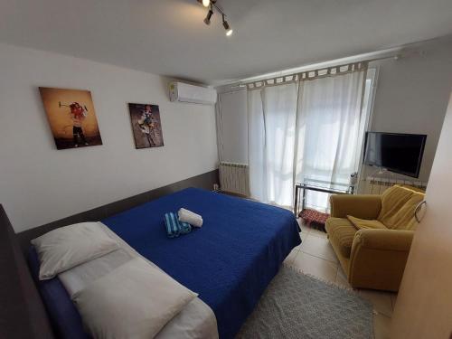 a small bedroom with a blue bed and a chair at Skradin villa et studio in Dubravice