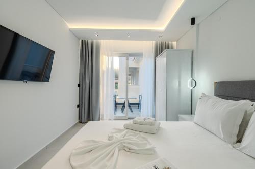 a white bedroom with a bed with two towels on it at Metsikas Residence in Limenas