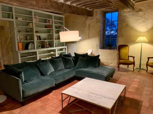 a living room with a green couch and a table at La Breteche du Perche in Saint-Germain-de-la-Coudre