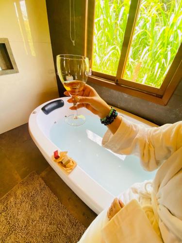 a person holding a wine glass in front of a window at Chale com hidro na Serra da Mantiqueira in Sapucaí-Mirim