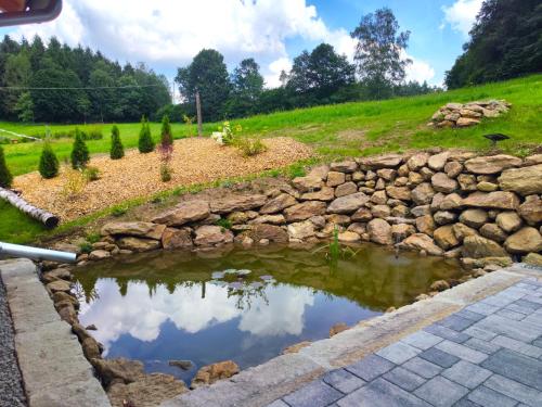a pond with a rock wall next to a field at VroniChalets - Tiny Chalets mit Sauna in Neukirchen