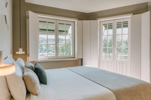 a bedroom with a large bed with two windows at Casa das Lérias in Amarante