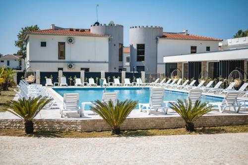 a pool with white lounge chairs and a building at M&N Holiday Resort in Ulcinj