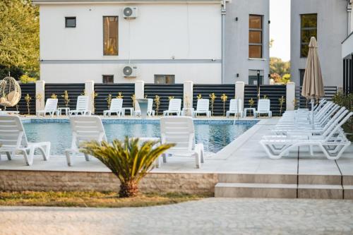 a row of white chairs next to a swimming pool at M&N Holiday Resort in Ulcinj