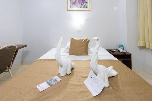 two white statues are on top of a bed at Rede Andrade Mirante in Foz do Iguaçu