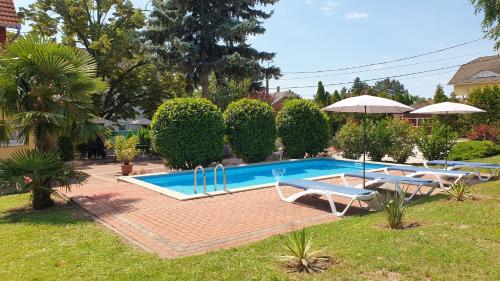 a pool with chairs and umbrellas in a yard at Éden Villa Apartmanház in Balatonfüred