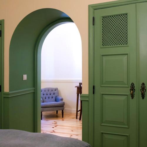 a room with a green door and a blue chair at York House Lisboa Hotel in Lisbon
