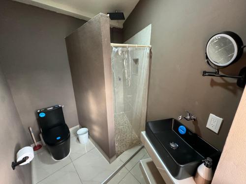 a bathroom with a shower and a black toilet and sink at Tiny Room El Mangal B&B in Suchitoto
