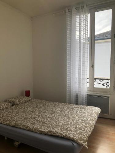 a bedroom with a bed and a large window at Chambre de 9m2 in Bagnolet