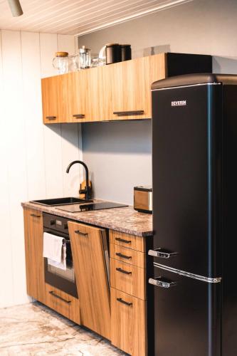 a kitchen with a black refrigerator and wooden cabinets at Dirhami jacuzzi villa in Spithami