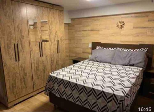 a bedroom with a large bed and wooden cabinets at casa jardim Eliza in Foz do Iguaçu