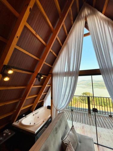 a large room with a tub and a large window at Chalés Paraíso do Lago in Itá