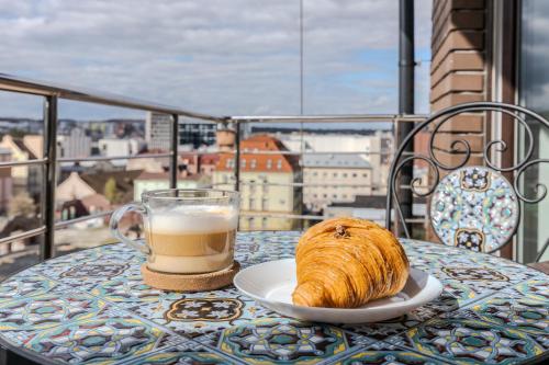a cup of coffee and a croissant sitting on a table with a glass at Old City apart in Lviv