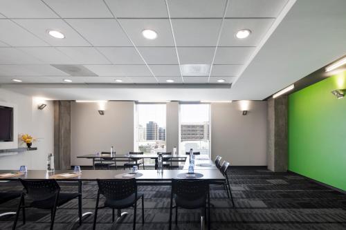 a conference room with tables and chairs and a green wall at Alt Hotel Winnipeg in Winnipeg