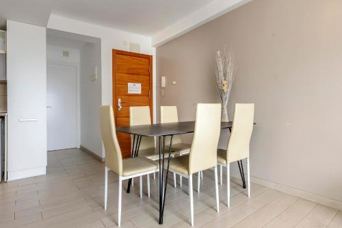 a dining room with a black table and yellow chairs at Apartamentos Esmeralda Ibiza in Ibiza Town