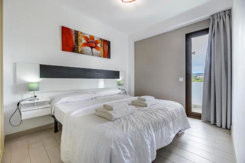 a white bedroom with two beds and a window at Apartamentos Esmeralda Ibiza in Ibiza Town