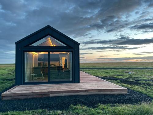 a small house with a large window on a field at Infinity Horizons in Hvolsvöllur