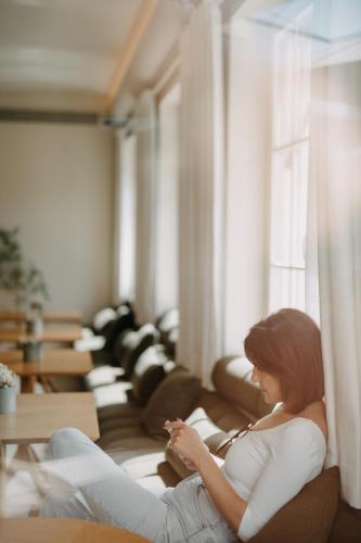 a woman sitting on a couch looking out a window at Casa das Lérias in Amarante