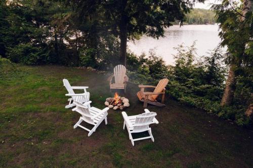 a group of chairs and a fire pit in the grass at Grinmore Lakehouse with Panoramic View & Hot Tub in Emsdale