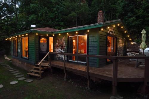 a green tiny house with lights on a deck at Grinmore Lakehouse with Panoramic View & Hot Tub in Emsdale