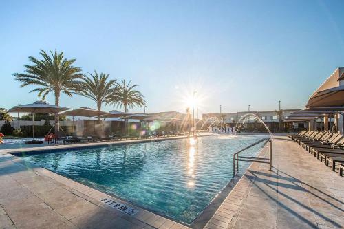 a large swimming pool with palm trees and umbrellas at Luxury Home in Orlando with private Hot Tub - 7 Min from Disney Parks - 3 bedrooms and 4 bathrooms! in Orlando