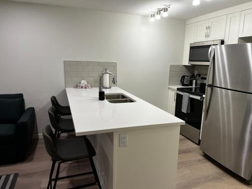 a kitchen with a white counter and a refrigerator at The Haven - cozy 1 bedroom suite in Seton SE Calgary in Calgary