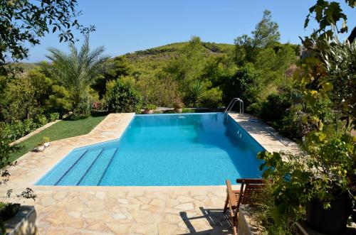 een zwembad in een tuin met een heuvel op de achtergrond bij Villa Pepy in Áyios Konstandínos