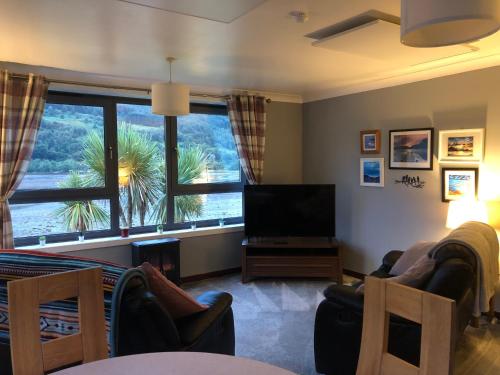 a living room with a tv and a large window at Heron’s View in Arrochar