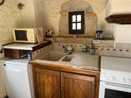 une cuisine avec un évier et un micro-ondes dans l'établissement L'Écrin Champêtre, gîte à la campagne, à Saint-Affrique