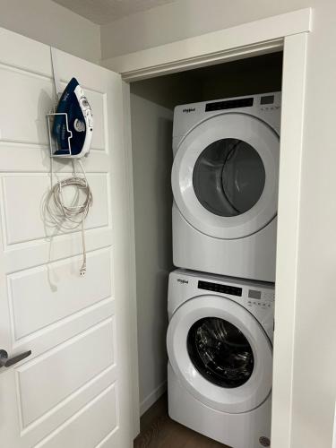 a laundry room with a washing machine and a washer at The Haven - cozy 1 bedroom suite in Seton SE Calgary in Calgary