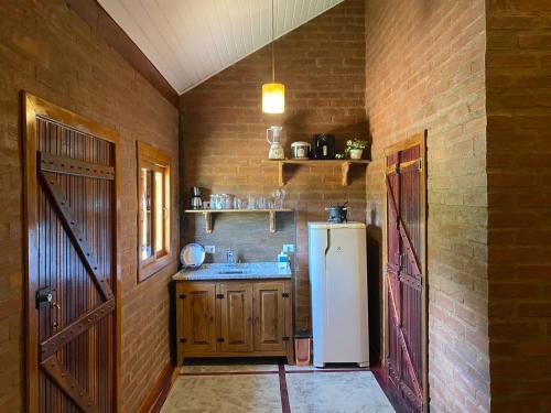 a kitchen with a refrigerator and a brick wall at Chale com hidro na Serra da Mantiqueira in Sapucaí-Mirim