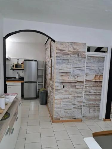 a kitchen with a stone wall and a refrigerator at Maison familiale avec piscine à Baie-Mahault - 120 m² - 8 pers in Baie-Mahault