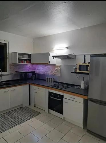 a kitchen with white cabinets and a stove top oven at Maison familiale avec piscine à Baie-Mahault - 120 m² - 8 pers in Baie-Mahault