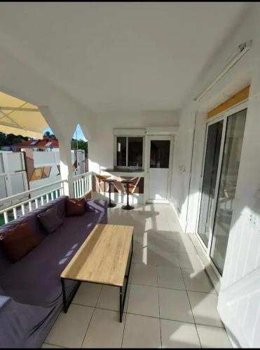 a living room with a wooden table on a balcony at Maison familiale avec piscine à Baie-Mahault - 120 m² - 8 pers in Baie-Mahault