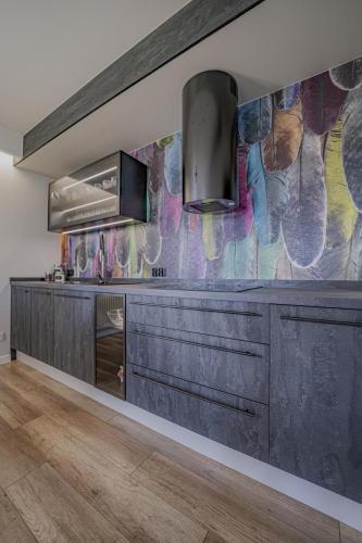 a kitchen with black cabinets and a colorful wall at Apartament w Cieplicach Elegant in Jelenia Góra