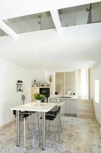 une cuisine blanche avec une table et des chaises dans l'établissement La Maison De Marius Saint Amour Bellevue, à Saint-Amour-Bellevue