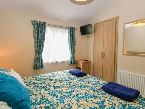 a bedroom with a bed with blue pillows on it at 21 Norman Drive Lodge in Great Yarmouth