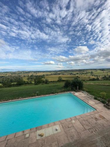 une grande piscine bleue avec un ciel nuageux dans l'établissement Maison Stirling Bourgogne Sleeps 8 Pool, à Saint-Julien-de-Civry