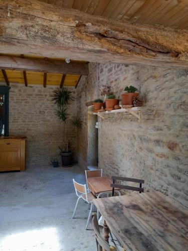 Cette chambre est dotée d'une table, de chaises et d'un mur en pierre. dans l'établissement At The End Of The World -bussieres Burgundy, à Bussières